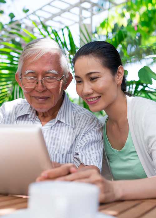 Father and daughter learning about assisted living communities on a tablet near Grand Villa of Port Charlotte in Port Charlotte, Florida