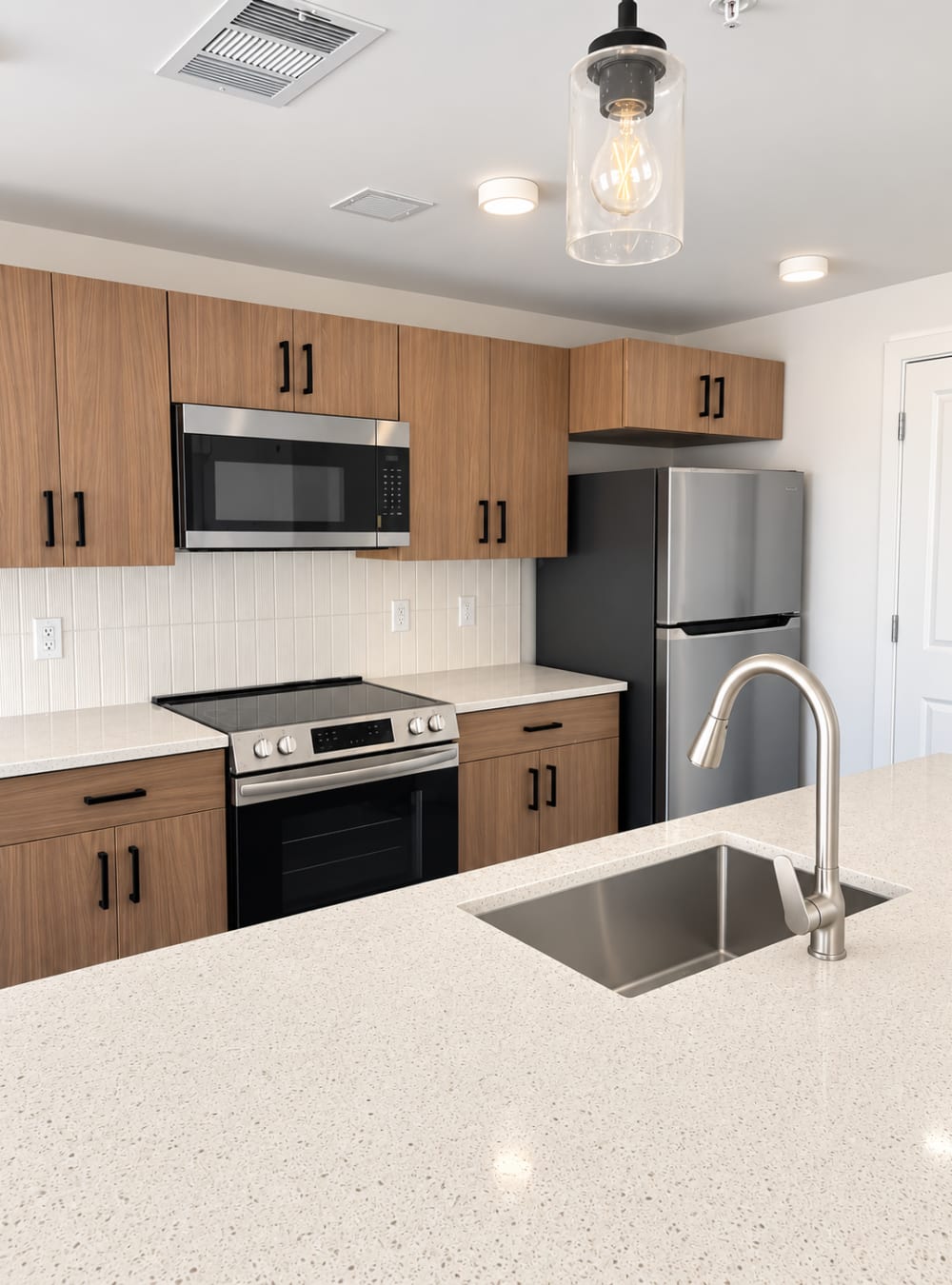 Contemporary kitchen with quartz backsplash, wood cabinets, and island sink at Altitude on Main in Richmond, Virginia