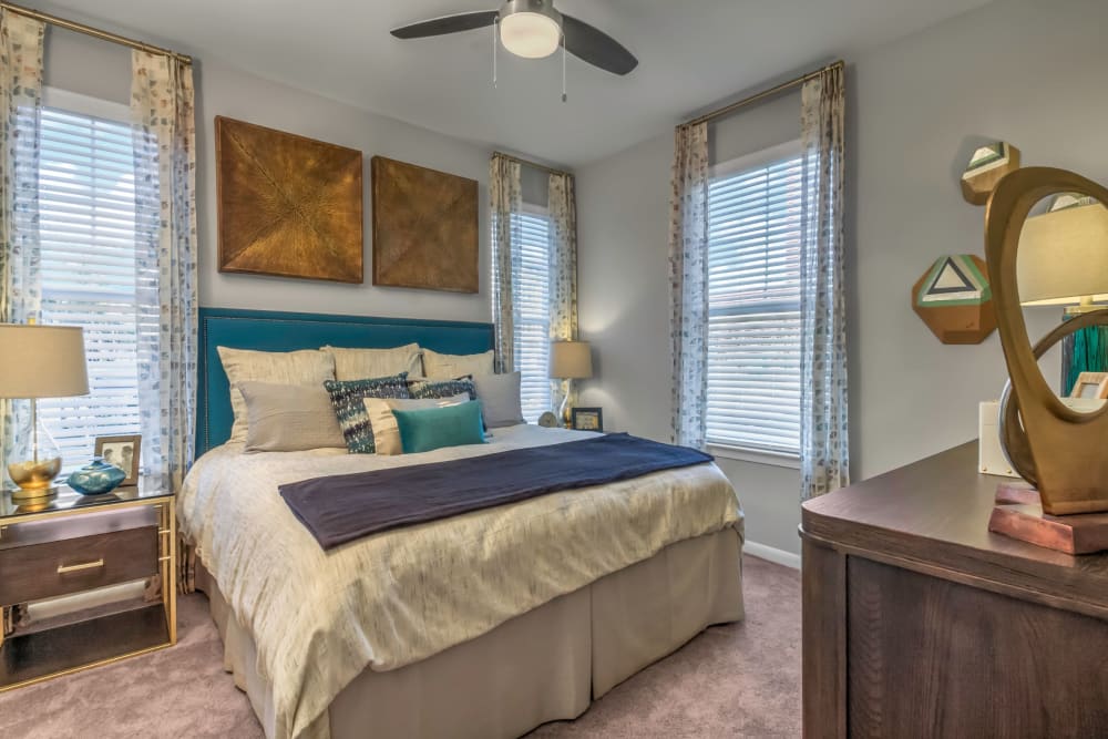 Master bedroom with a ceiling fan and an en suite bathroom in a model home at The Palmer in Charlotte, North Carolina