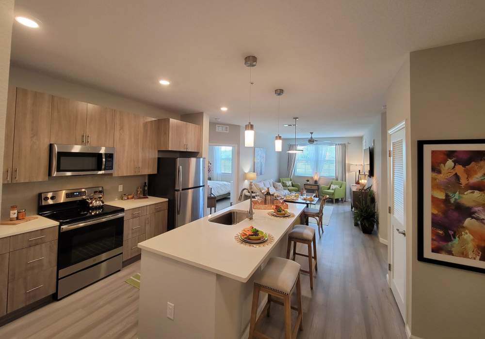 Modern kitchen with open layout and sunlit living area at Messina Luxury Apartments in New Smyrna Beach, Florida