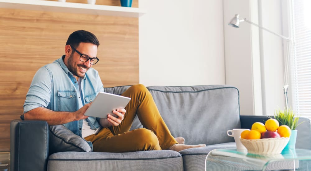 Resident man relaxing and working on his tablet or ipad in this living room in his home at Sorrento in Stockton, California