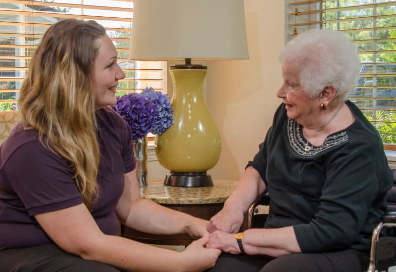 A caregiver and a resident holding hands at Carefield Living.
