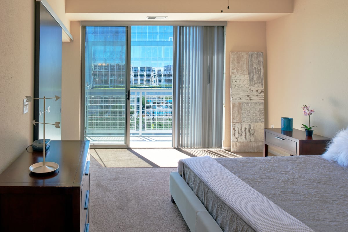 Apartment bedroom with a door out to a private balcony at Flux in Minneapolis, Minnesota