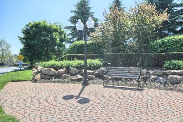 An inviting park bench on a sunny day near Legends Fox Creek in Clarkston, Michigan