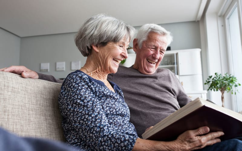 Couple looking at a photo album at Grand Villa of Deerfield Beach in Deerfield Beach, Florida