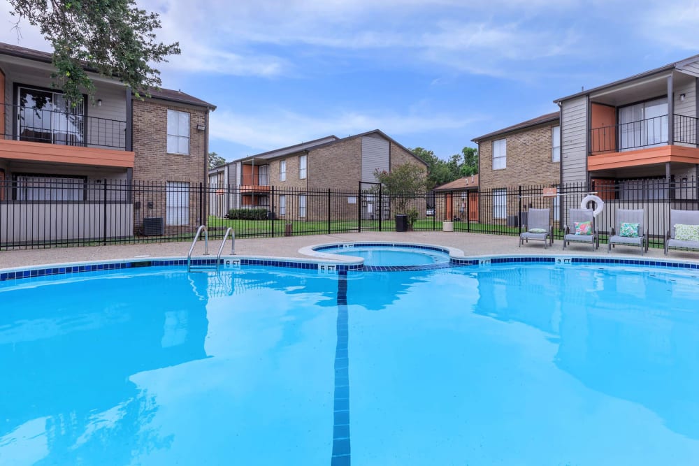 Lounge chairs by the sparkling swimming pool at CrescentWood Apartments in Clute, Texas