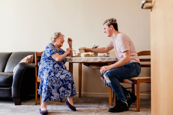 A resident enjoying a meal with her grandson in her home