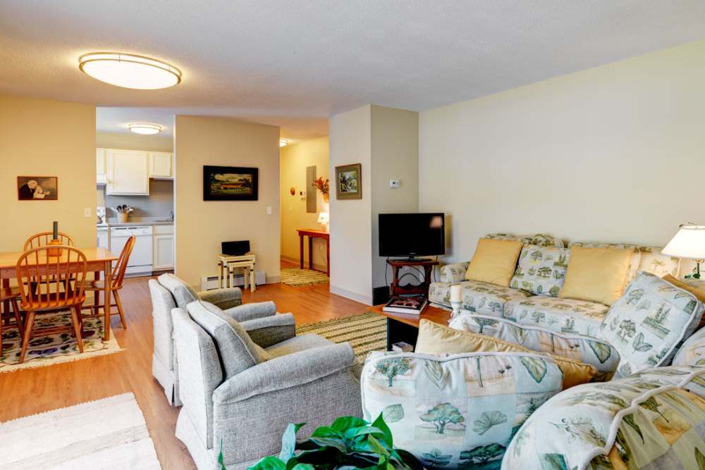 Spacious living room with large couch, chairs, coffee table and hardwood flooring at Middlebury Arms in Middleboro, Massachusetts