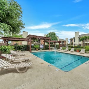 Swimming pool surrounded by lounge chairs at Stonegate Apartments in Mckinney, Texas