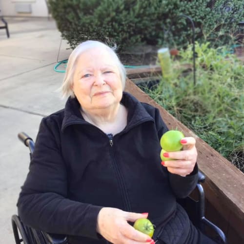 Resident holding fresh apples outside at Oxford Glen Memory Care at Grand Prairie in Grand Prairie, Texas