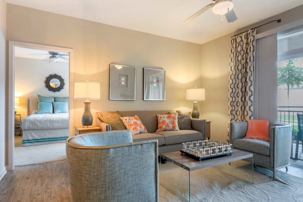 Model living room with hardwood-style floors opening onto a private balcony at The Village at Apison Pike in Ooltewah, Tennessee