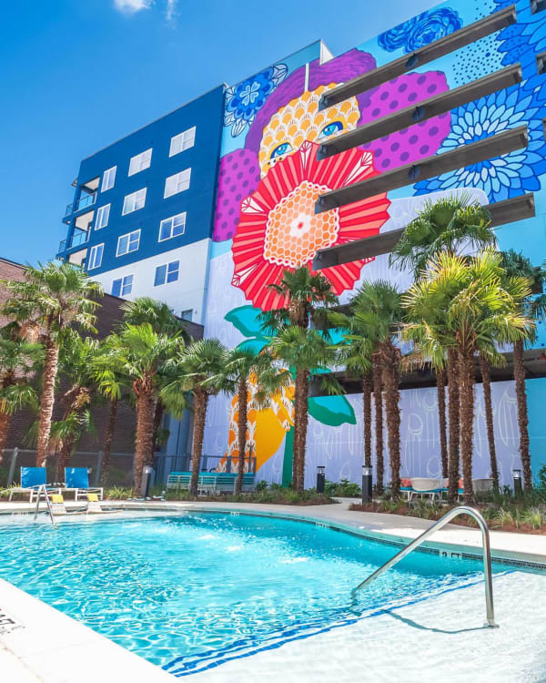 Sparkling pool surrounded by palm trees and a vibrant mural at EDGE on the Beltline in Atlanta, Georgia