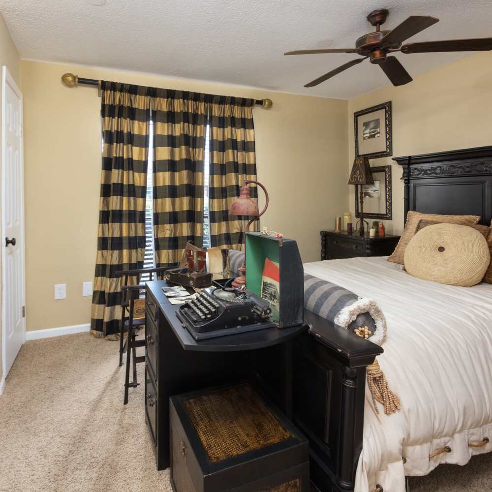 Spacious bedroom with a bed, ceiling fan, large window and a wooden table at The Arbors On Taylor in Montgomery, Alabama