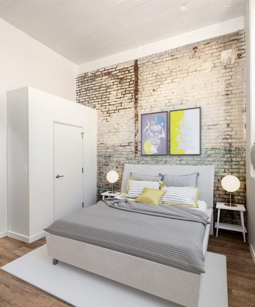 Bed with gray bedding and decorative pillows at Brush Factory Lofts in Philadelphia, Pennsylvania