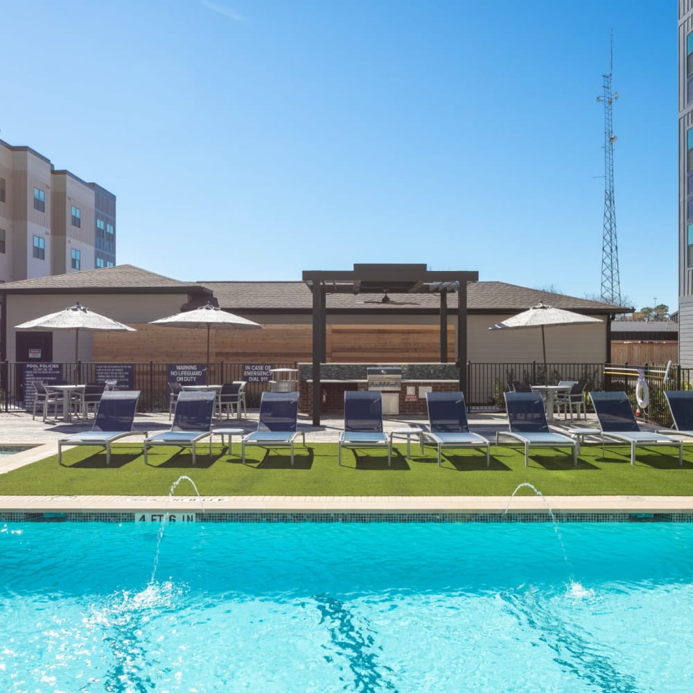 Beautiful inground community pool with lounge chairs and umbrellas at Bellrock Memorial in Houston, Texas