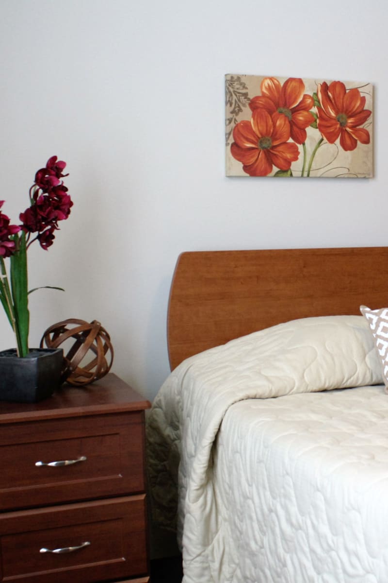 Resident bed with nightstand and food tray at East Troy Manor in East Troy, Wisconsin