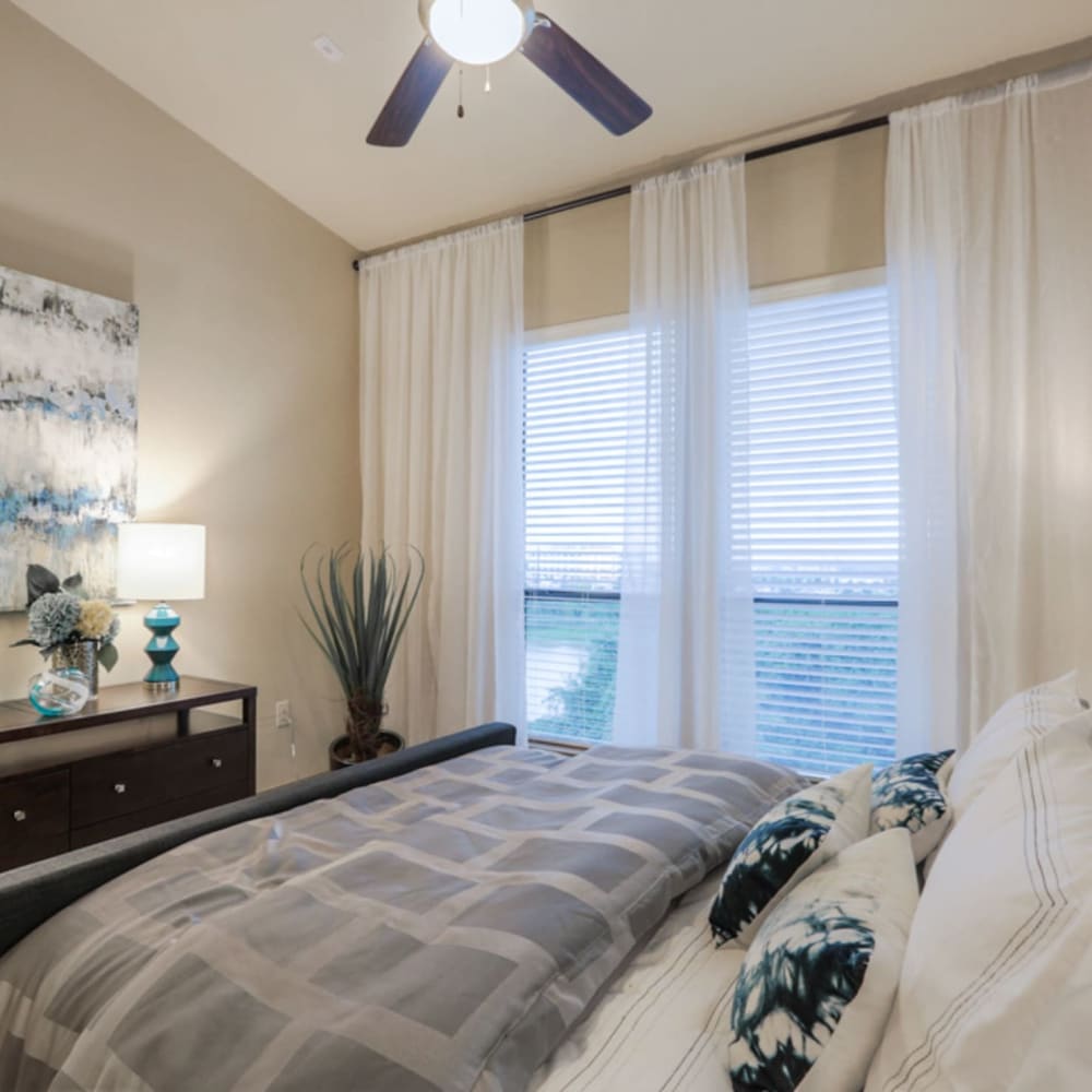 Model bedroom with a ceiling fan and large windows at Imperial Lofts in Sugar Land, Texas