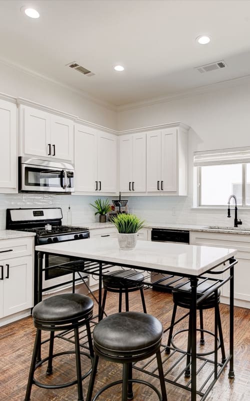 Modern eat-in kitchen with bright white cabinets and hardwood flooring at The Collection Townhomes in Dallas, Texas