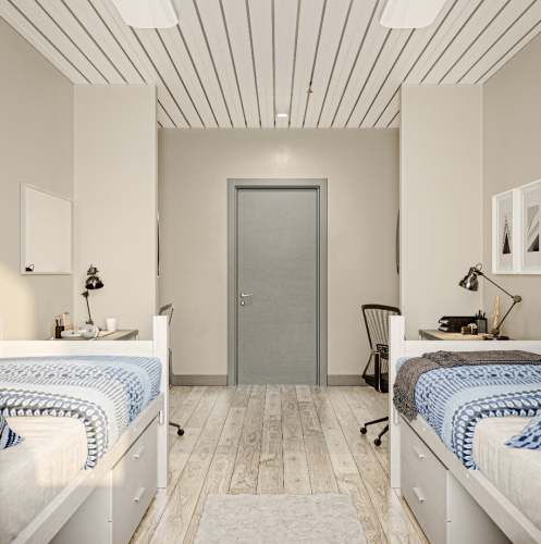 Bedroom with two beds opposite and attached study tables at Polly O'Meara Doyle Hall in Santa Rosa, California