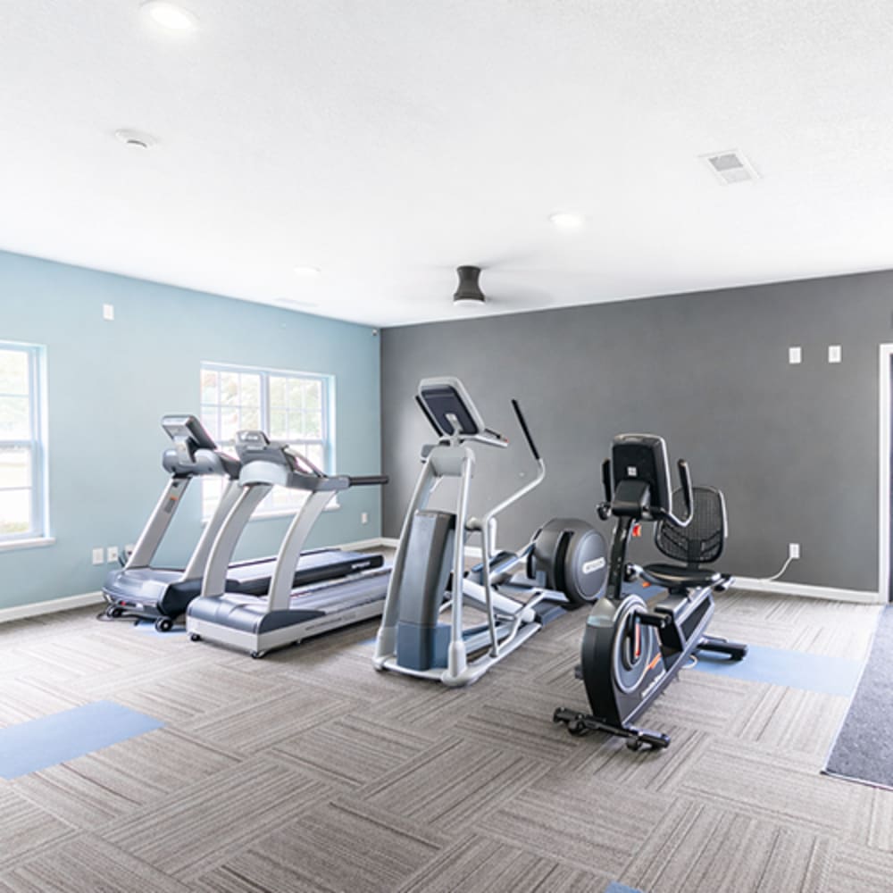 Bright fitness center with modern equipment and carpeted at Somerset Park Apartments in Bath, Michigan