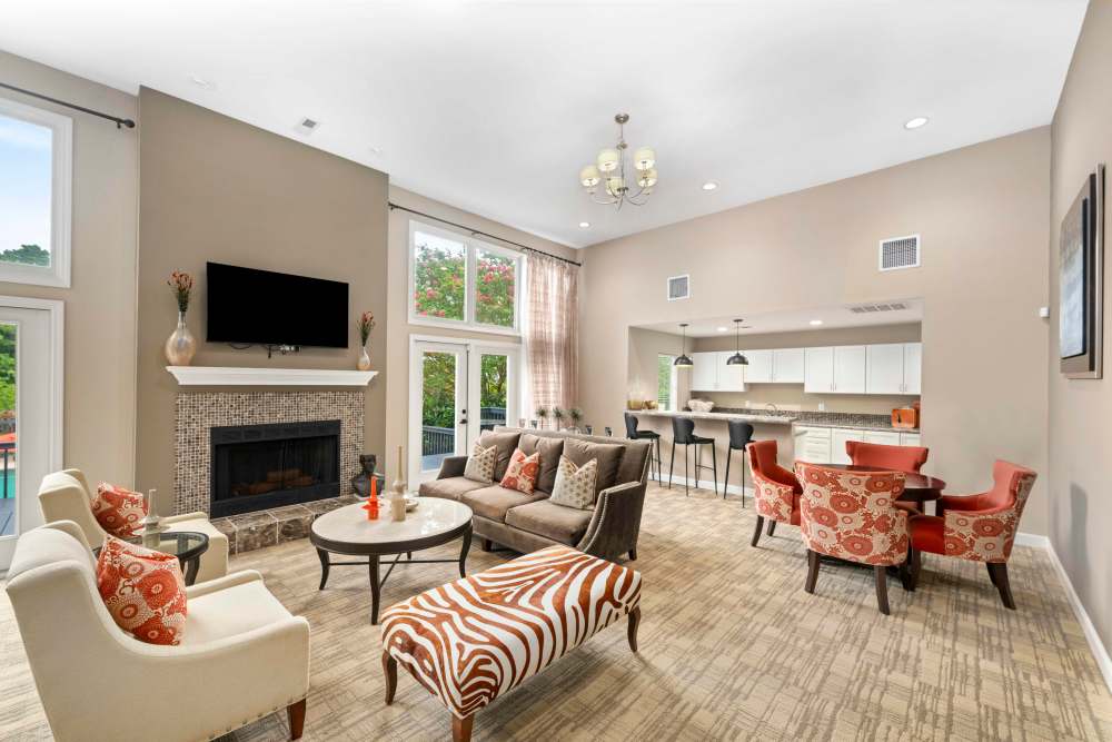 Spacious living room with couch, coffee table, chairs, entertainment center, and plush carpeting at The Ellery of Cary in Cary, North Carolina