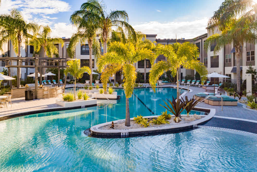 Sparkling water pool surrounded by lush landscaping and inviting lounge areas at The Walton in Sanford, Florida.