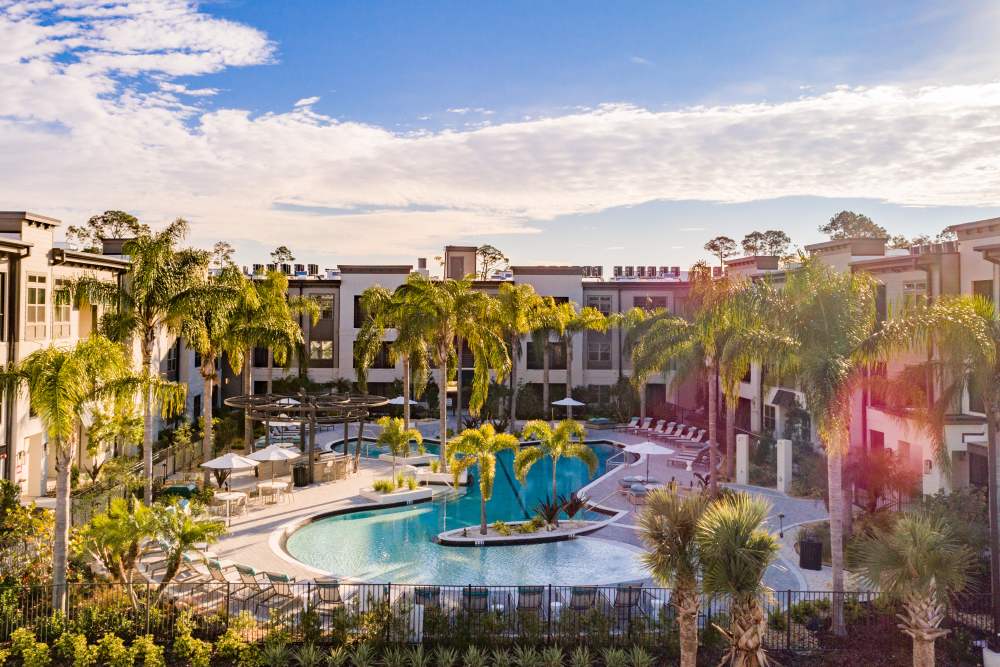Resort-style living with a sparkling water pool surrounded by lush landscaping at The Walton in Sanford, Florida.