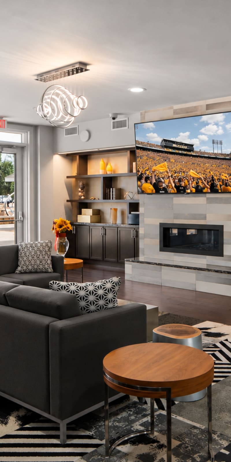 Modern clubhouse with sofa and tv with a stylish overhead light at The Den in Columbia, Missouri