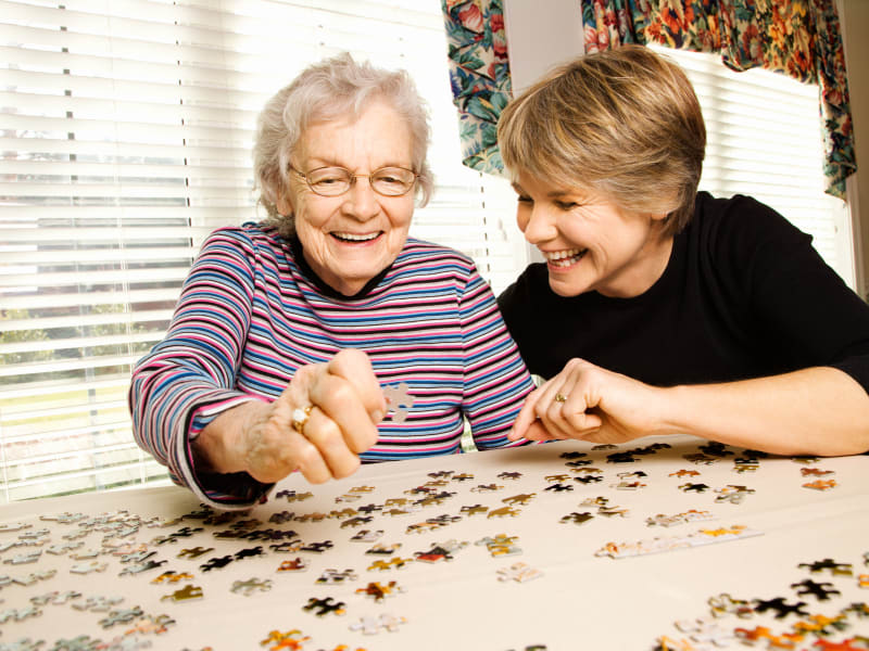 Resident working on a puzzle with her daughter at The Residences on Forest Lane in Montello, Wisconsin