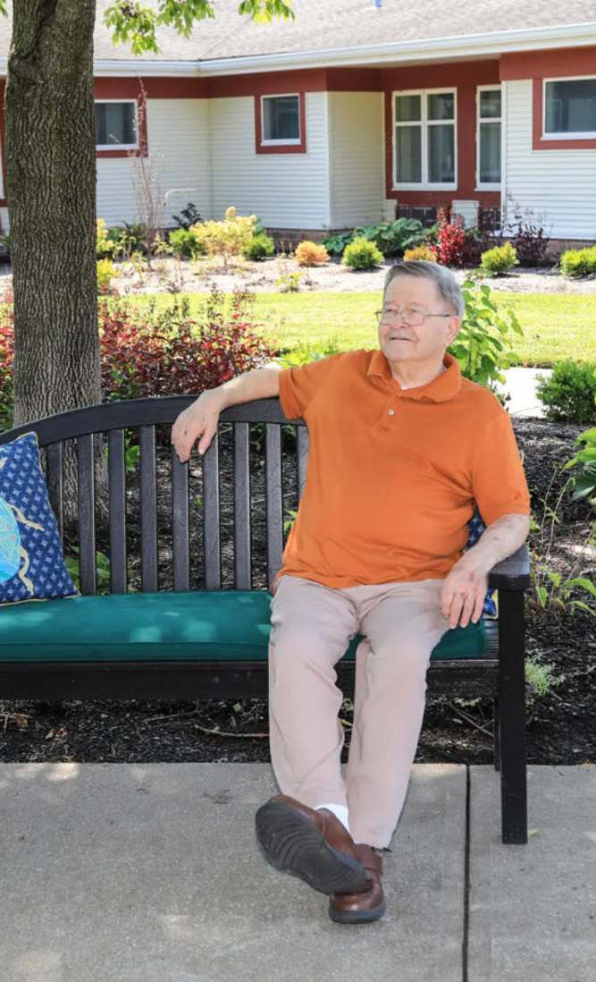 Resident playing outside on a bench enjoying the gardens at Garden View Care Center in St. Louis, MO