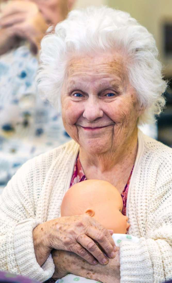 Resident holding a doll and smiling at Garden View Care Center in St. Louis, MO