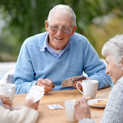 Group of residents playing cards outdoors at Oxford Vista Wichita in Wichita, Kansas