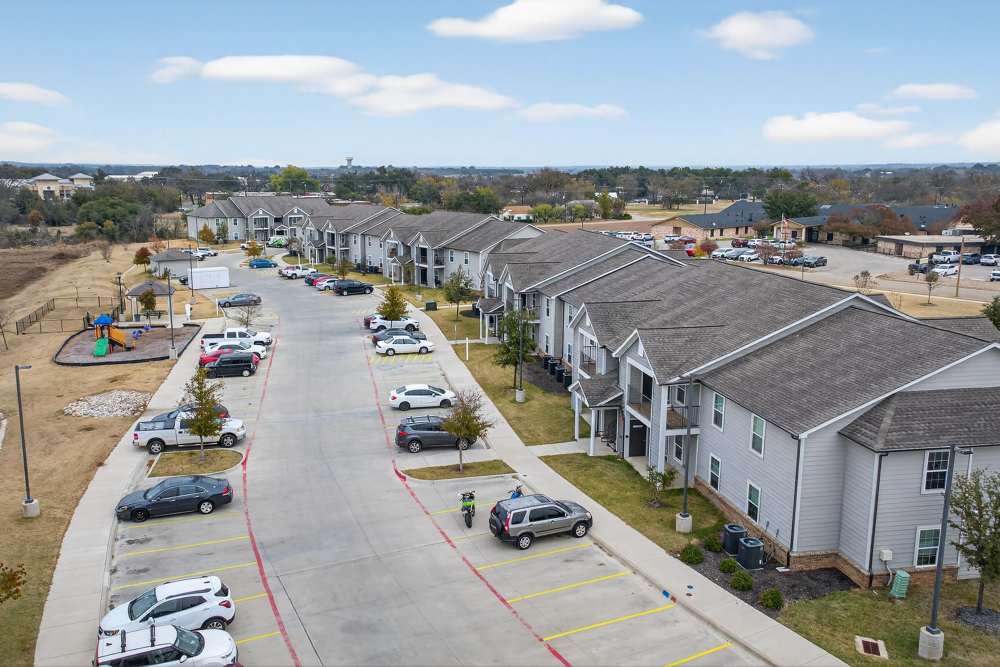Charming apartment community with lush landscaping and a vibrant playground at Lakewood Crossing in Granbury, Texas.