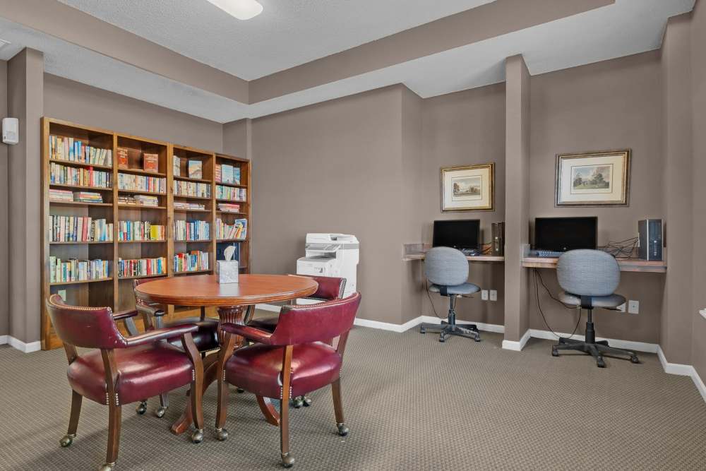 Charming reading nook with a cozy atmosphere, surrounded by shelves of books and modern workstations at Rolling Meadows Apartments in Glenpool, Oklahoma.