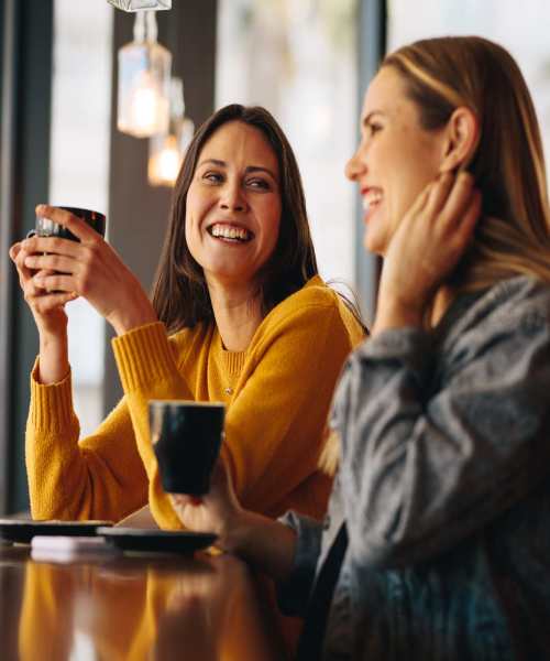 Two woman laughing at a table near Lemon Bay Apartments in Englewood, Florida