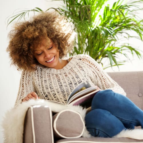 A resident setting on her couch and reading a book at Chollas Heights Historical in San Diego, California