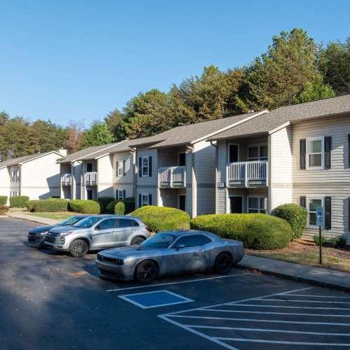 Apartment community with balconies, manicured landscaping, and parked cars in a spacious lot at Pleasant View Apartments in Charlotte, North Carolina