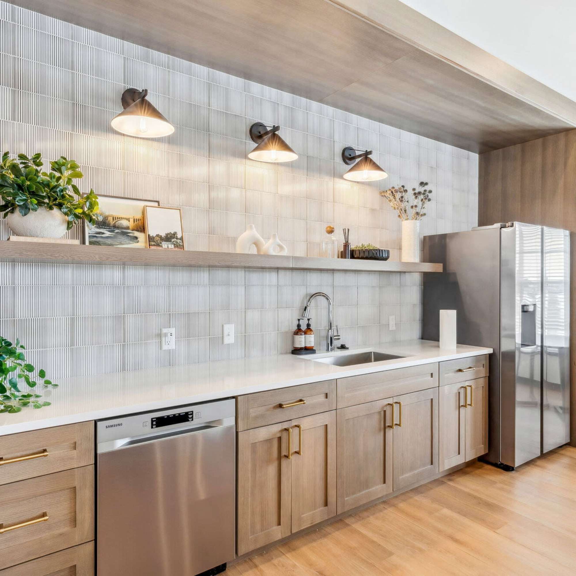 Modern kitchen with granite countertops, stainless steel appliances, wood-style flooring, and stylish pendant lights at The Mills in Sidney, Ohio