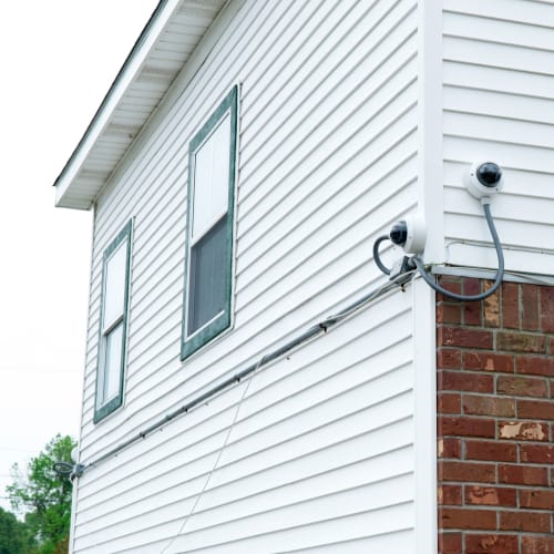 Security camera mounted on a white building with brick at Red Dot Storage in Baker, Louisiana