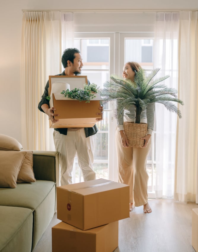 Couple carrying moving boxes into their new apartment near a StoreLine self storage location