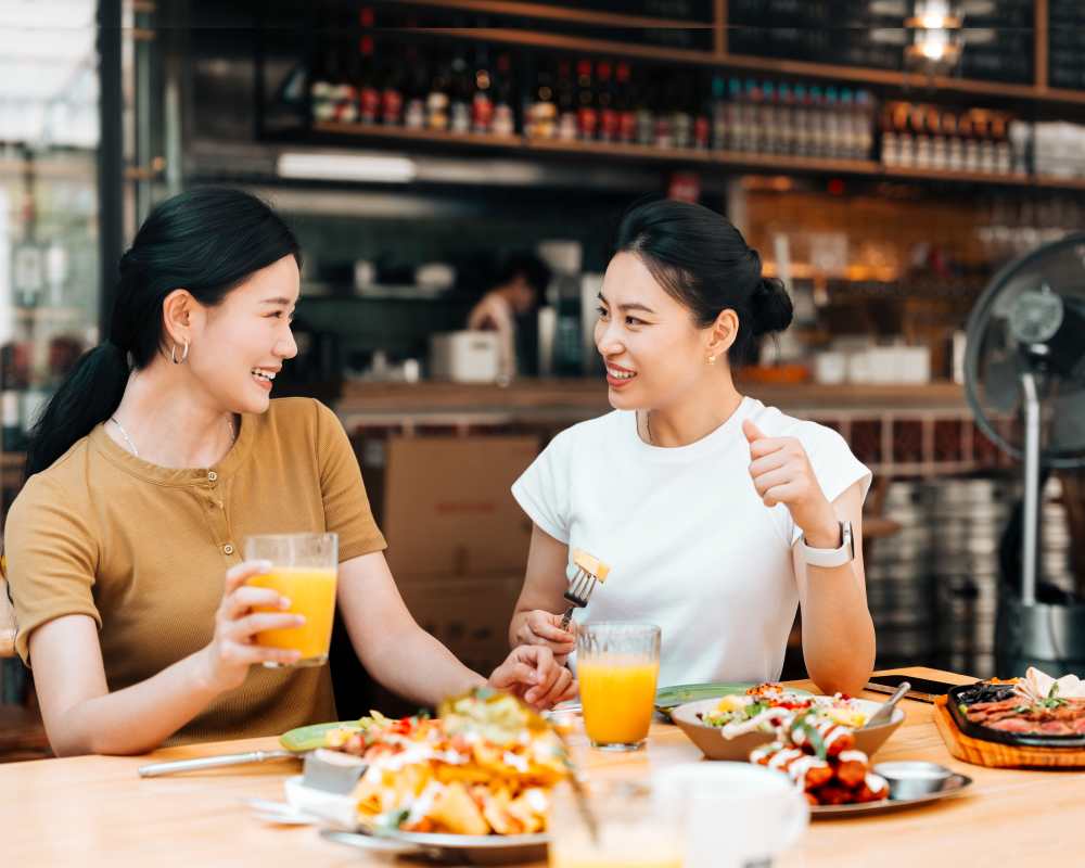 Two women enjoying brunch at a table filled with colorful dishes and drinks at Exhibit at J Town in San Jose, California