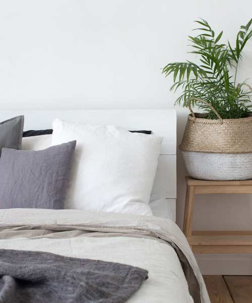 A well-made bed and side table with a plant at Copper Steppe in Parker, Colorado