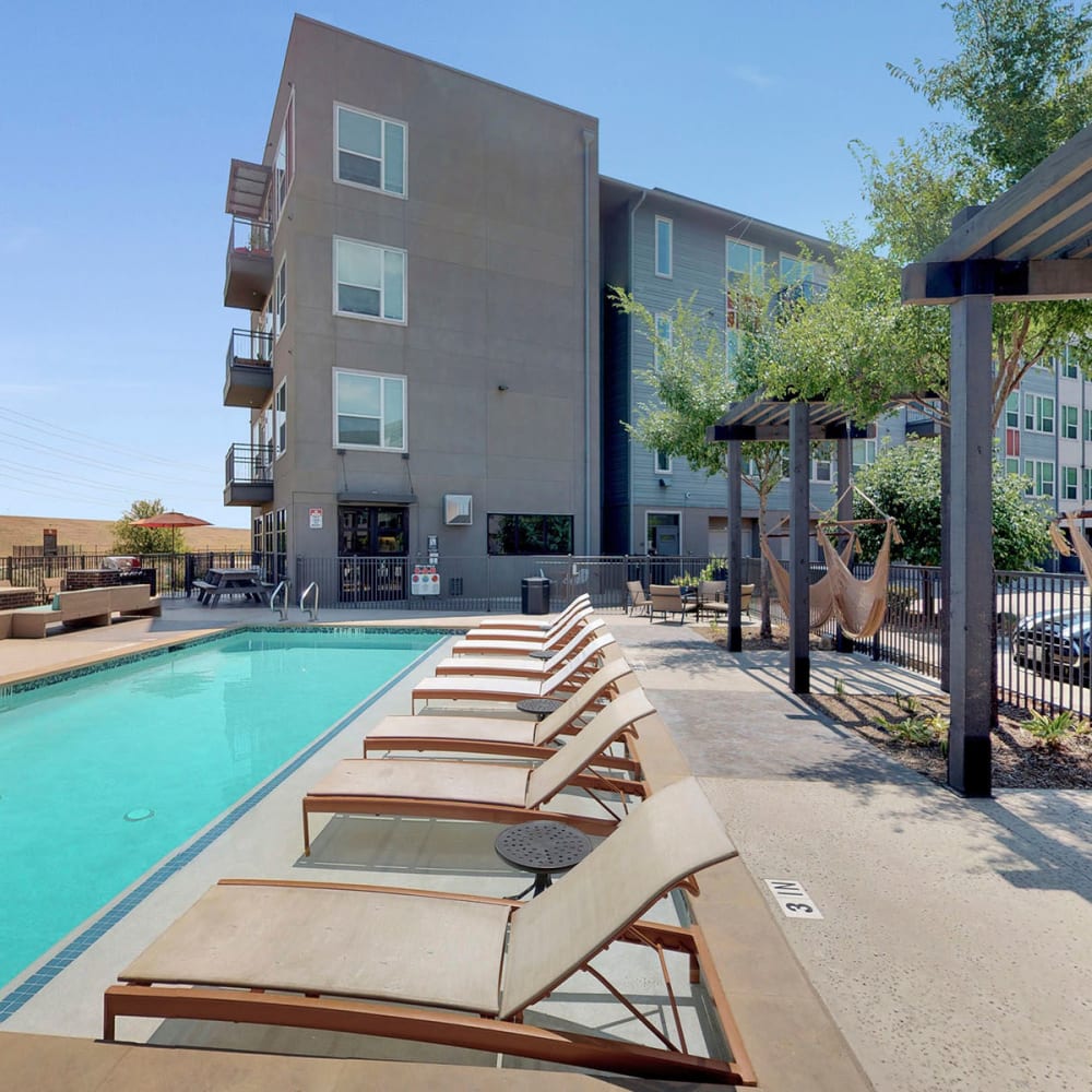 Swimming pool flanked by lounge chairs and hammocks at Oaks Trinity in Dallas, Texas