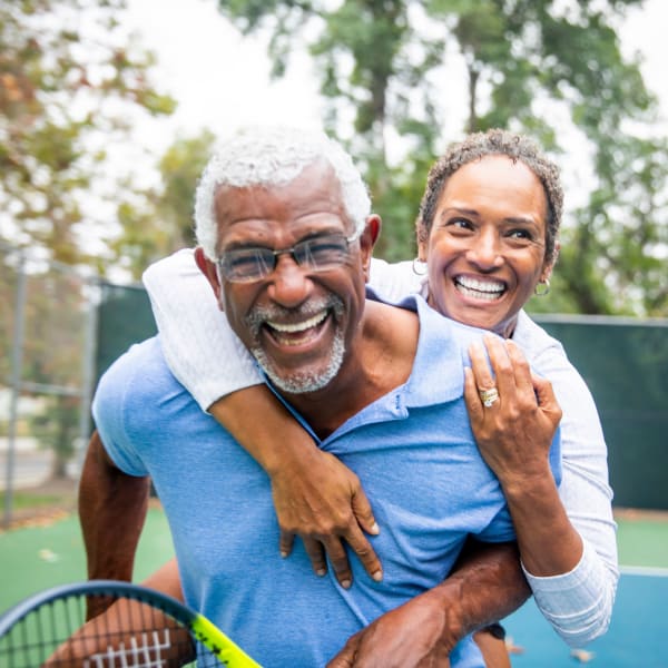Resident holding tennis racket being embraced at Pacifica Senior Living Ellensburg in Ellensburg, Washington.