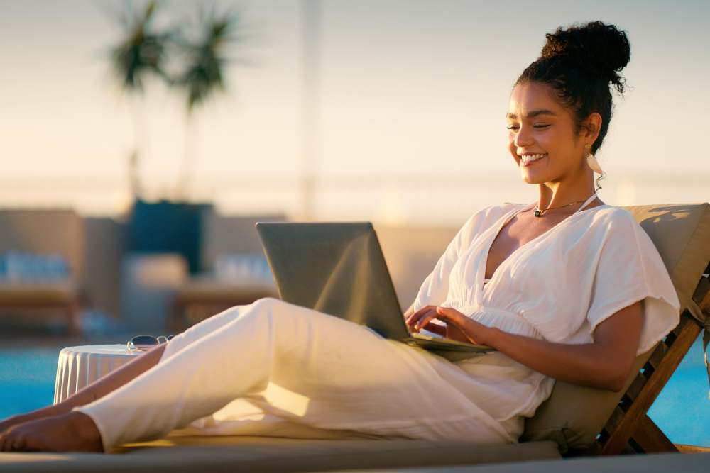 Woman working on laptop by pool at Romero Apartments in Pensacola, Florida