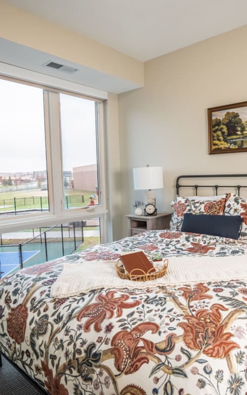 Resident bedroom with full size bed and large window at The Pillars of Lakeville in Lakeville, Minnesota