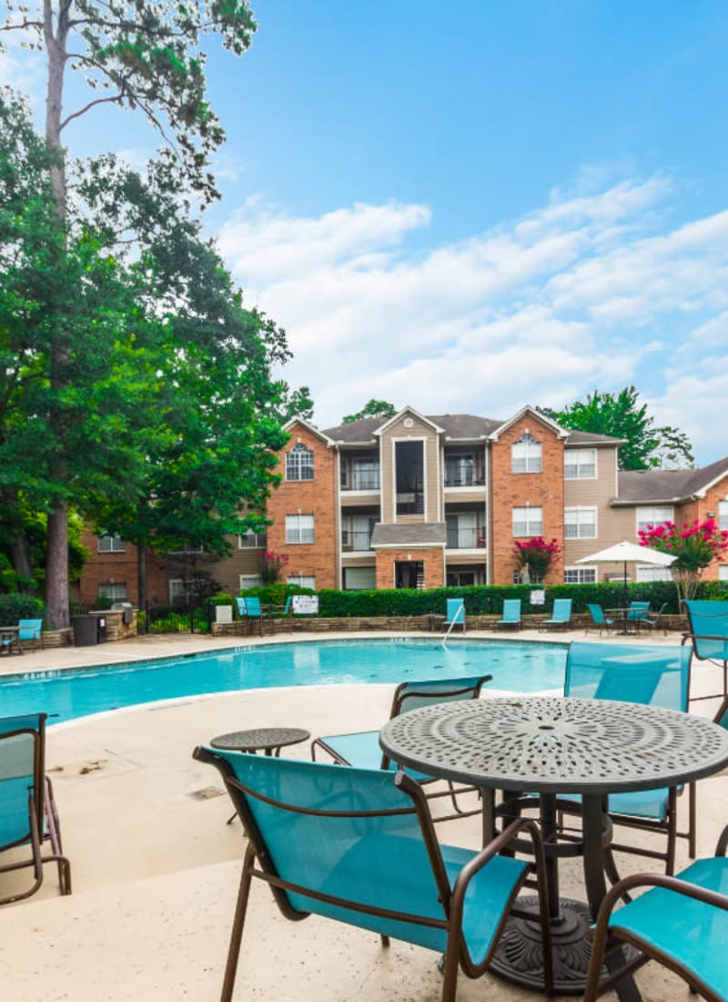 Overlooking pool and patio lounge chairs and tables at Marquis at Kingwood in Kingwood, Texas