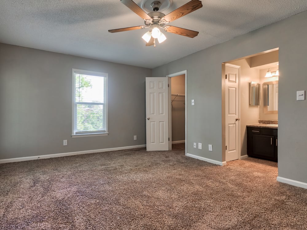 bedroom and connected bathroom with ceiling fan at The Gatsby at Midtown Apartment Living in Montgomery, AL