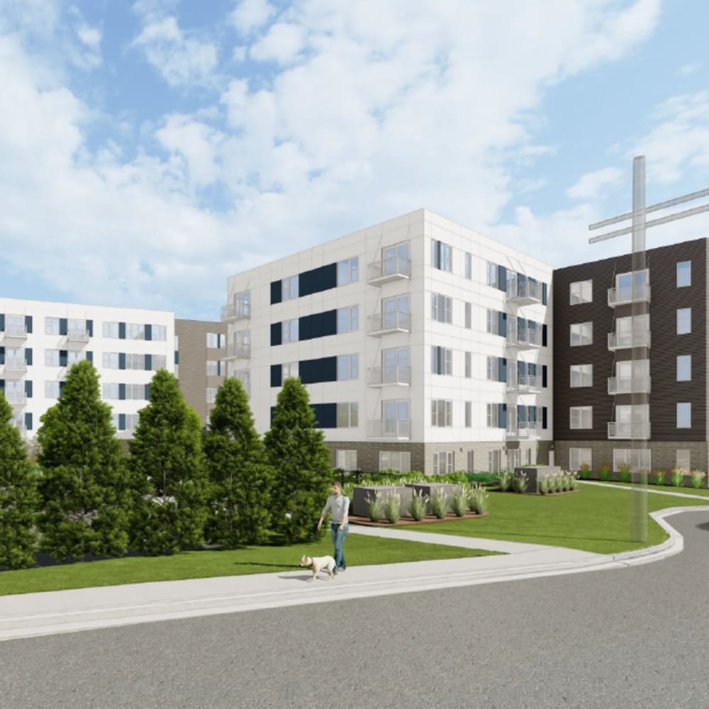 Exterior view of apartment with white and brown facades, landscaped greenery, and a person walking a dog at The Intersect in Madison, Wisconsin