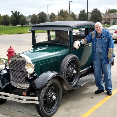 A Resident standing outside by an oldschool car at Glen Carr House Memory Care in Derby, Kansas